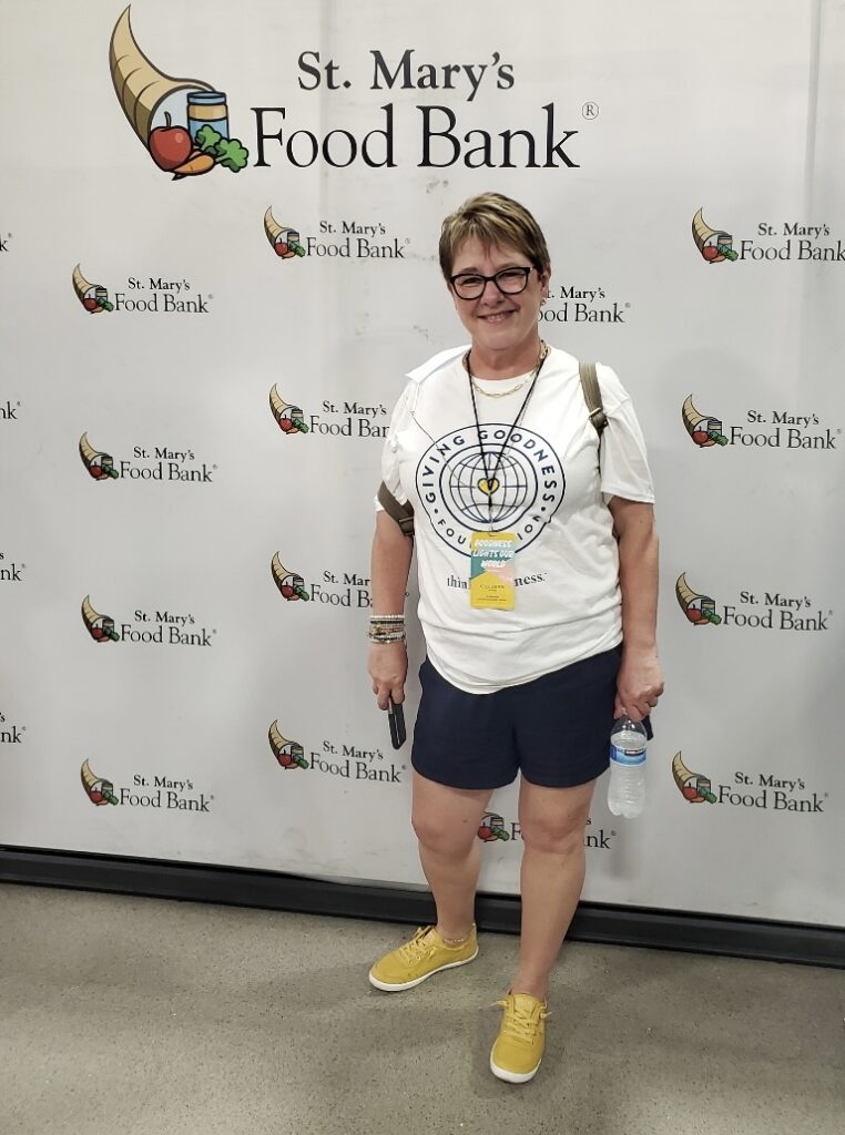 A picture of Colleen Evans standing in front of St. Mary’s Food Bank in Phoenix, Arizona. Think Goodness founders and purpose partners were there for a day of goodness packing food hampers. This day was a part of a journey to a meaningful purpose and growth