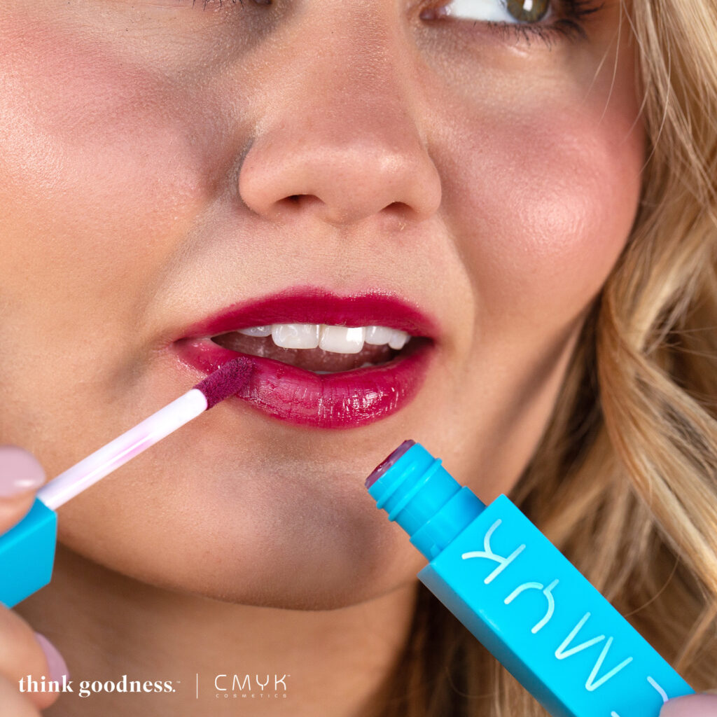 CMYK Cosmetics founder, Bella Lambert applying lip gloss to her lips