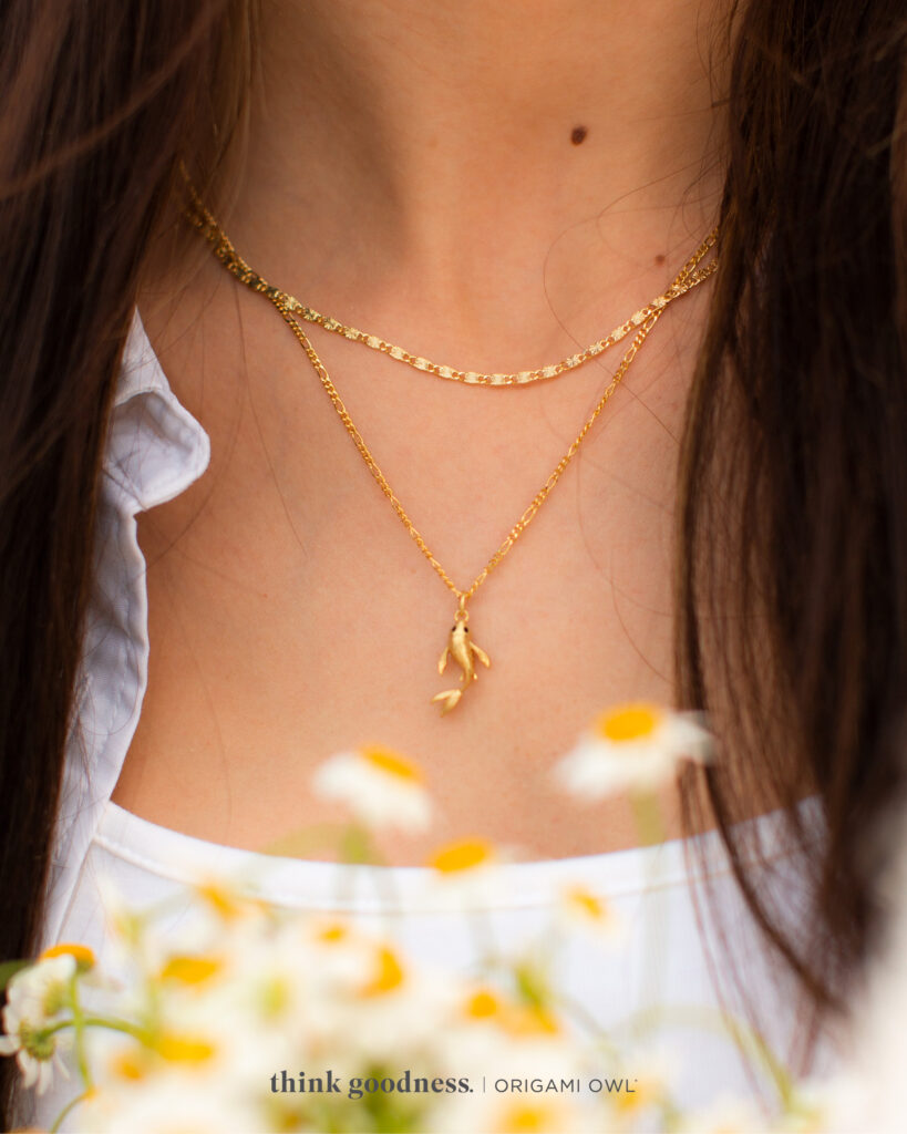 Woman wearing koi fish necklace in gold and a gold chain from spring collection