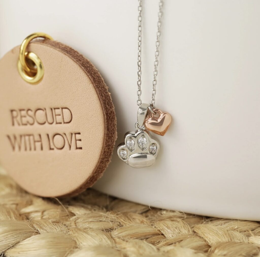 A paw and heart necklace with a round wooden circle that says rescued with love will make a purr-fect Mothers Day gift ideas for fur moms