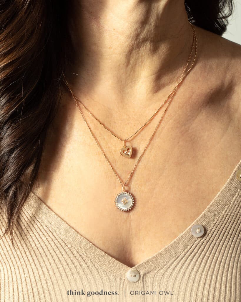 A woman in a beige top wearing a rose gold Birthstone heart pendant and a life is a gift pendant on chains