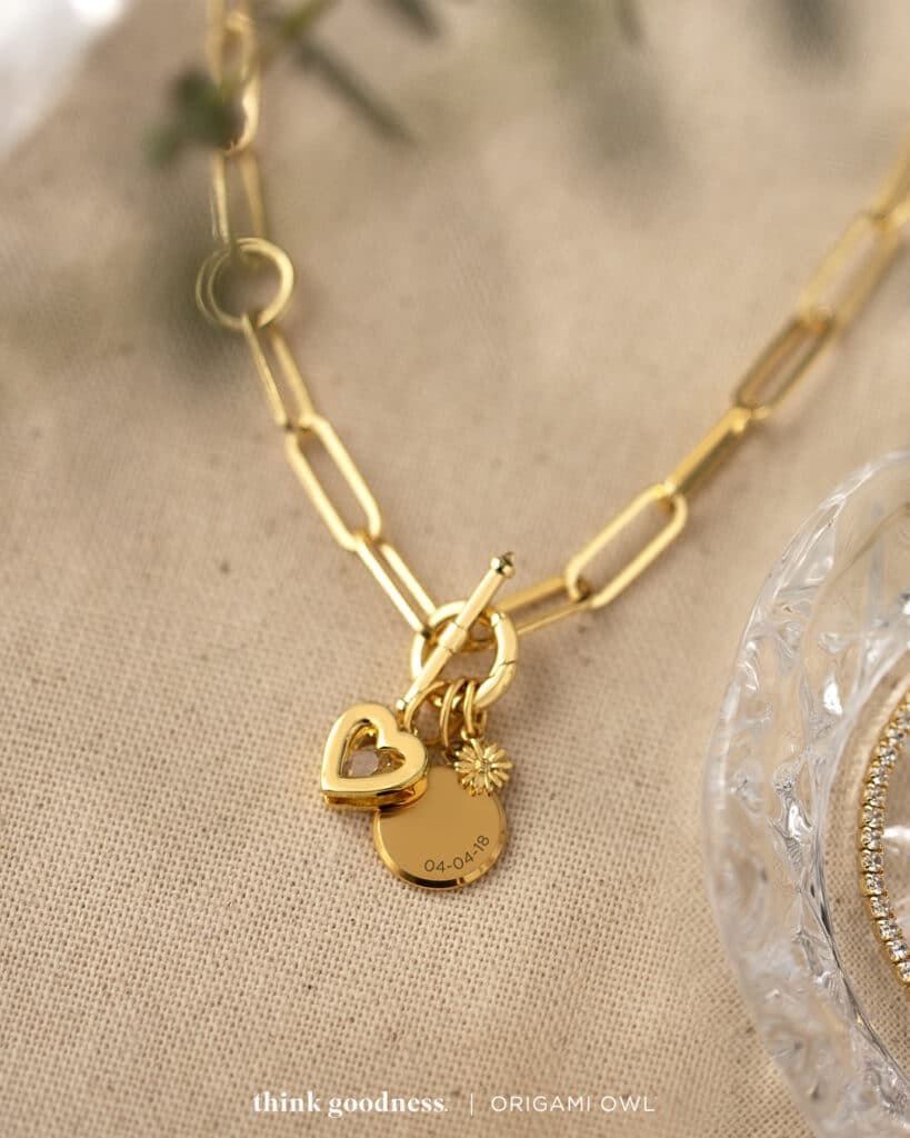 Gold paper link toggle chain with a gold heart pendant and a gold round inscription pendant on chains 