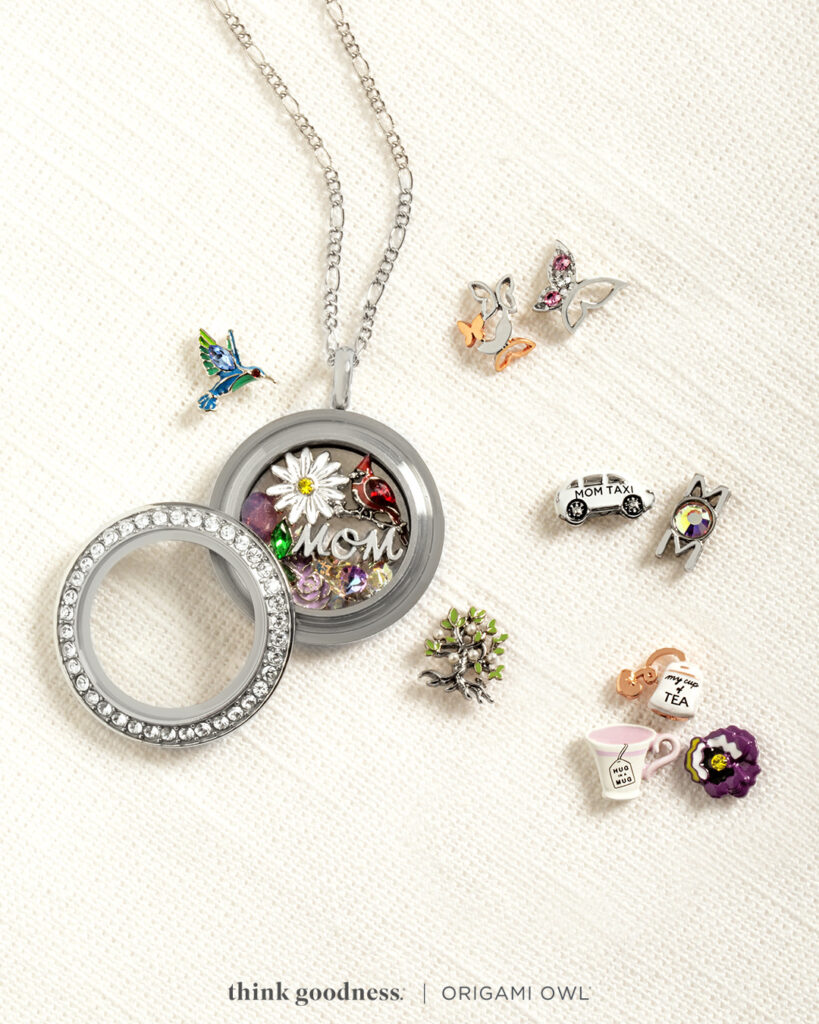 A silver Living Locket with the locket face lying acros the locket full of charms and chars. Surrounding the locket 