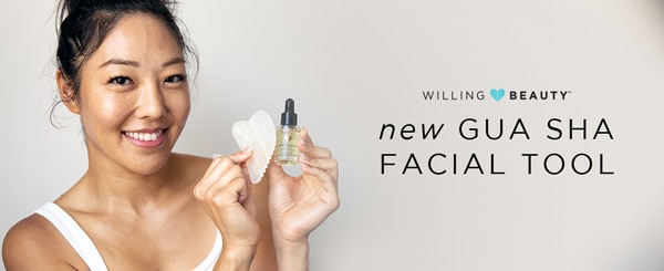 an image of a woman smiling holding a gua sha facial tool in one hand and a bottle of willing beauty born to glow skin elixir in the other hand with verbiage ' willing beauty - new gua sha facial tool