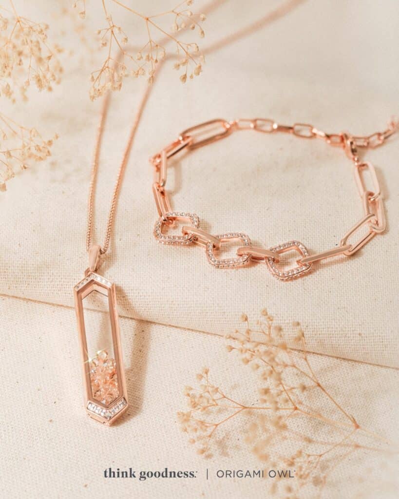 A white background with rose gold leaves with the rose gold baguette vertical bar living locket set and the rose gold pave link paperclip chain bracelet for fall season 2023