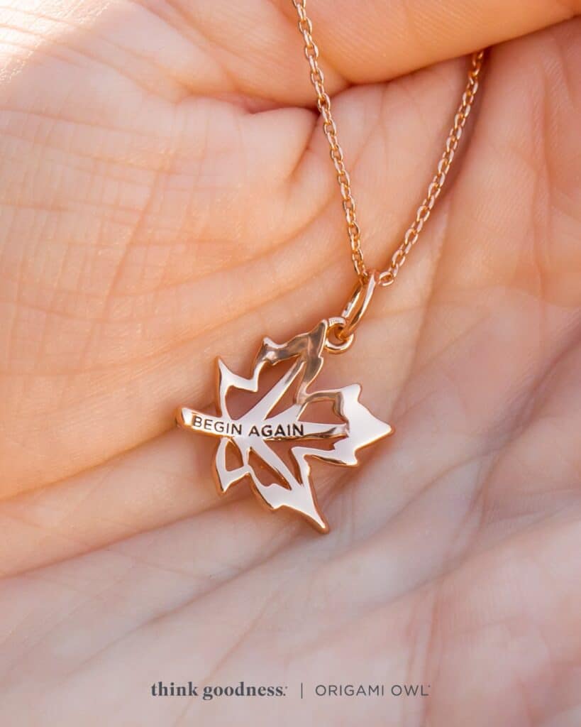 a person's hand holding the rose gold begin again pendant necklace for fall season 2023. this is the back of the pendant