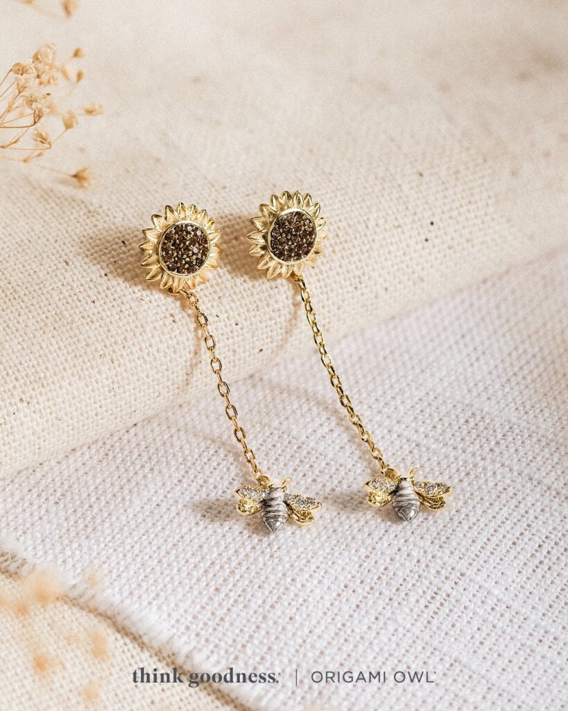 An off white image with beige foliage with our fall jewelry trends sunflower and bee drop earrings