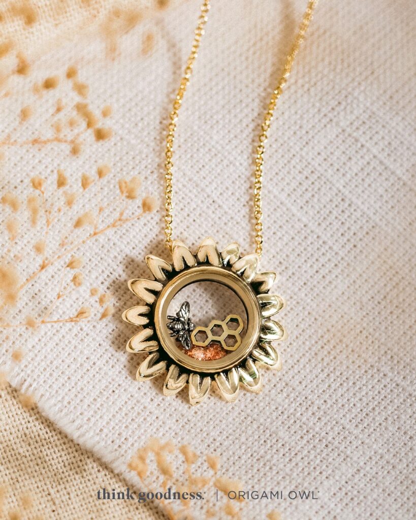 an off white background with beige foliage and the Origami Owl Sunflower Capsule locket