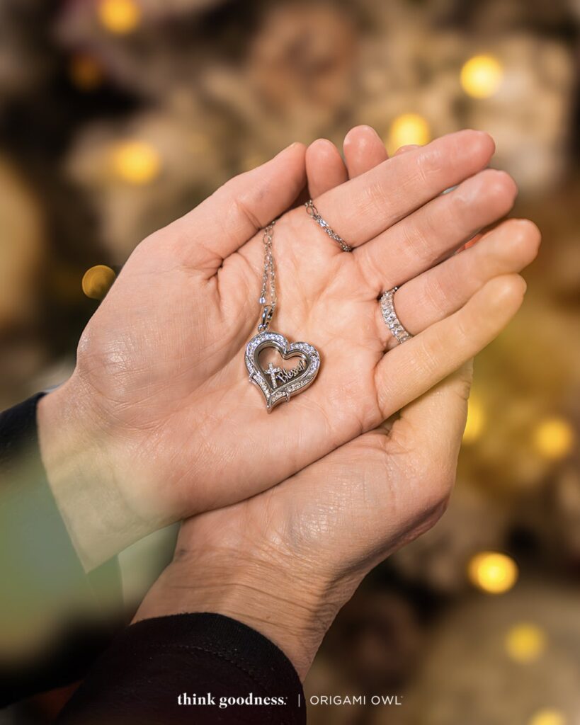 a pair of woman's hands on top of each other with the new slanted vintage heart living locket with a chain and a cross and blessed charms wearing a baguette ring