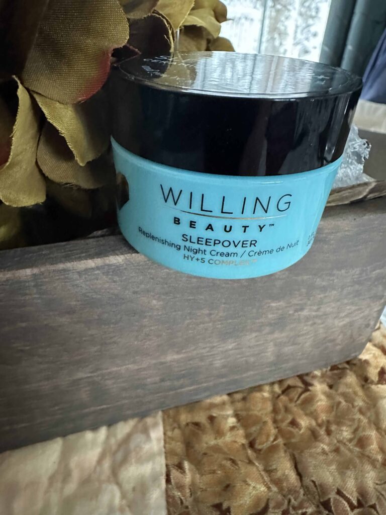 A gold flower background with a blue croc of Willing Beauty’s sleepover replenishing night cream that is an essential daily Skincare product