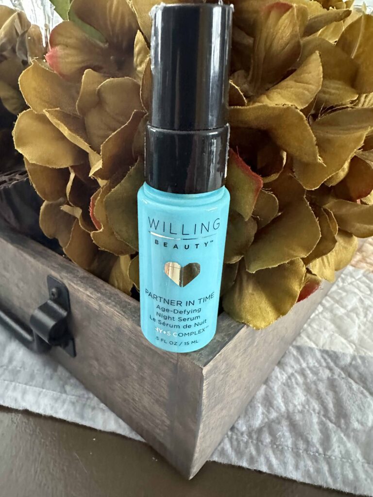 A gold flower background with a blue bottle of Willing Beauty’s partner in time age-defying night serumthat is an essential daily Skincare product