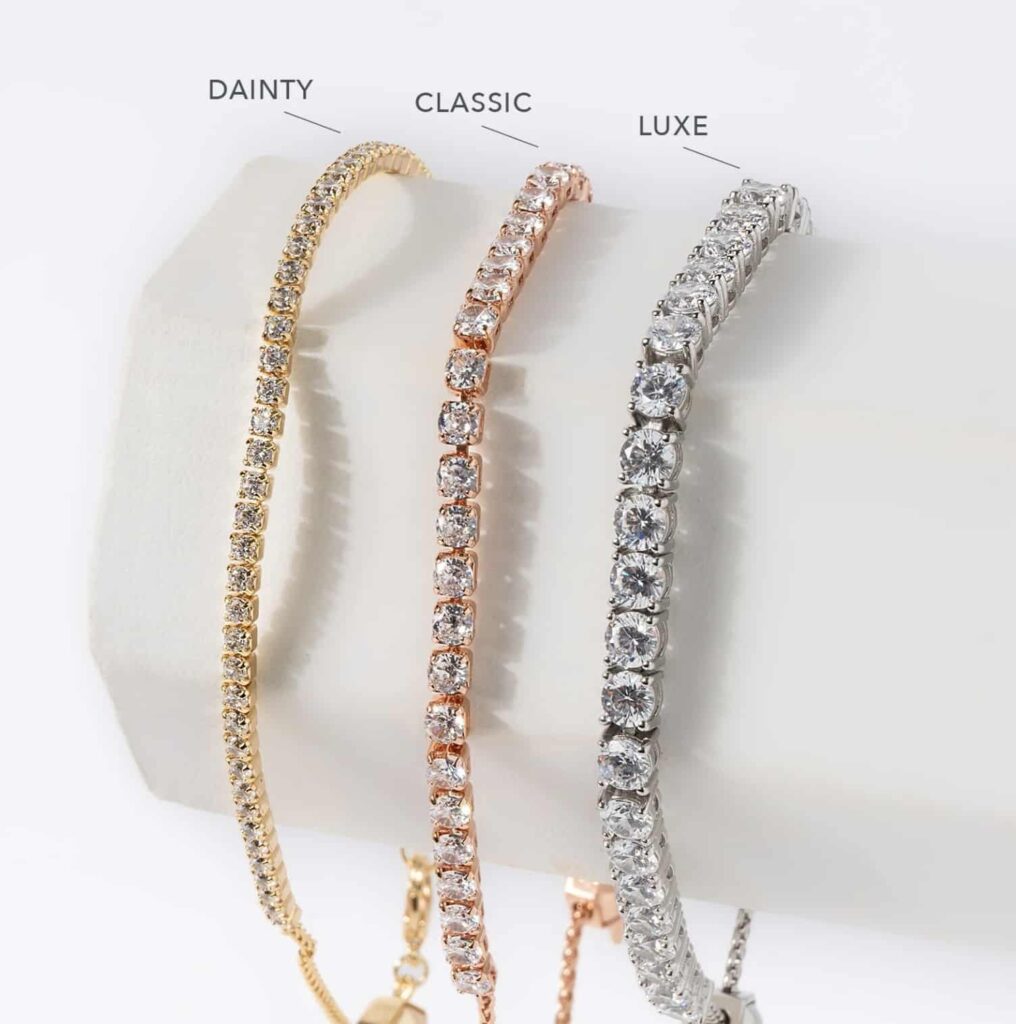 A bracelet holder with 3 tennis bracelets showing the differences of crystals: a gold dainty bolo bracelet showing dainty crystals, a rose gold classic bolo bracelet showing classic crystals and a silver luxe bolo bracelet showing luxe crystals